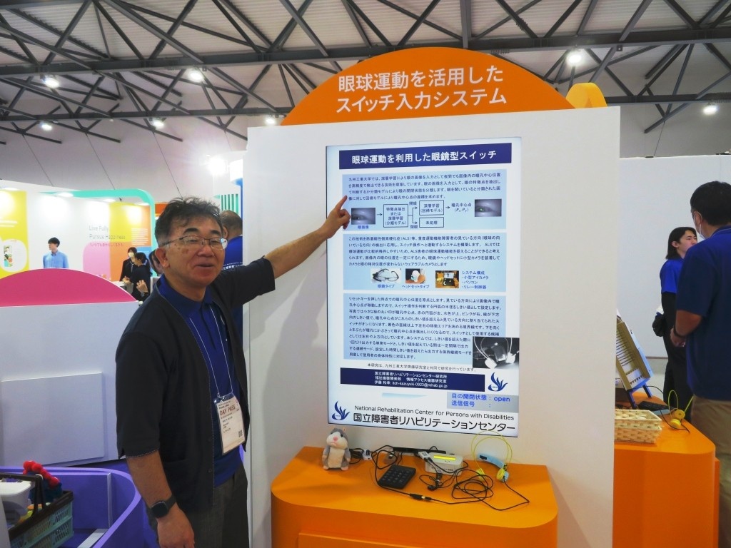 システム説明パネルを指さす共同研究者の伊藤氏