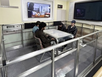 震度7の揺れを体験する留学生(後ろの映像では大きな家具が倒れています。)