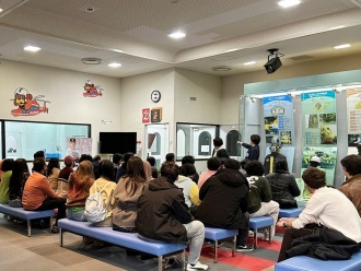 煙避難体験を目前に熱心に説明を聞く留学生